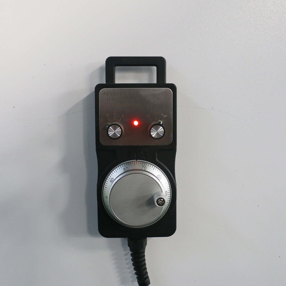 Handheld CNC controller with two dials and LED indicator, used for precision adjustments in CNC machinery operations.