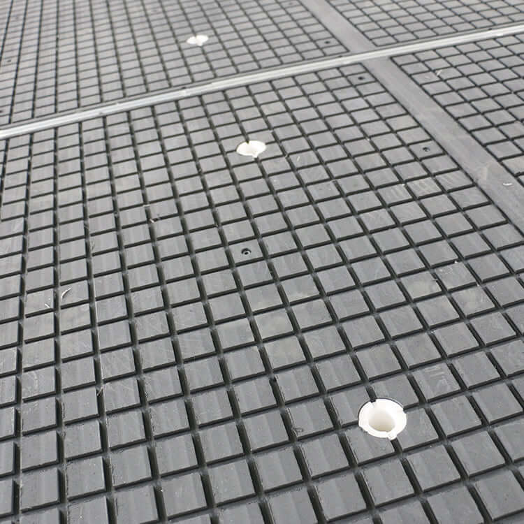 Close-up of a textured vacuum table surface on a CNC router machine for precise wood furniture processing.