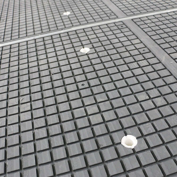 Close-up of a textured vacuum table surface on a CNC router machine for precise wood furniture processing.