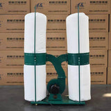 Industrial dust collector with dual filter bags, used for efficient dust removal in workshops. Green and white design.