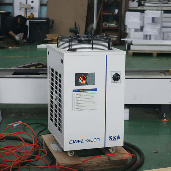 Industrial CWFL-3000 laser chiller for metal cutting machine, providing stable and reliable cooling in workshop setting.