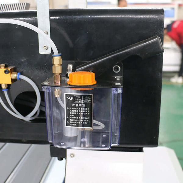 Close-up of an oil lubrication system with transparent reservoir and orange cap attached to machinery, showcasing industrial use.