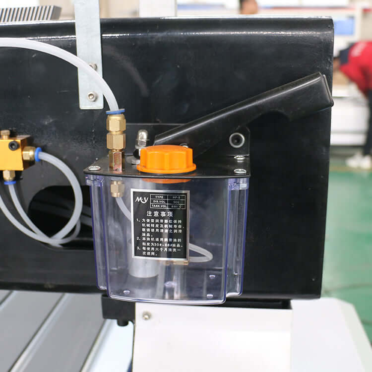 Close-up of an oil lubrication system with transparent reservoir and orange cap attached to machinery, showcasing industrial use.