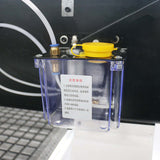 Close-up of an oil lubrication system with yellow cap and transparent container, showcasing mechanism and fluid lines.