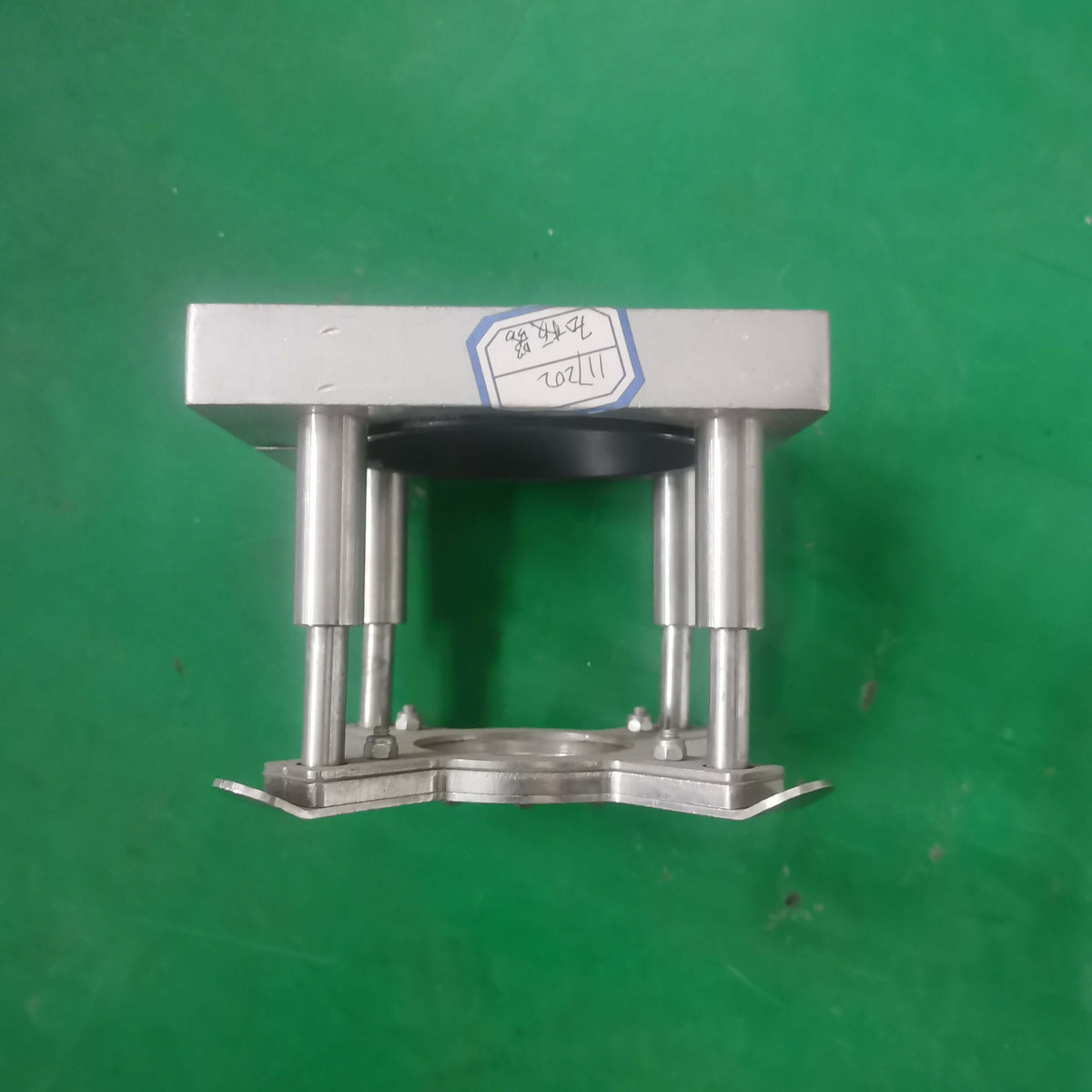 Metal platen press component on a green background.