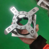 Close-up of a hand holding a silver metal platen press component with screws against a green background.