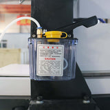 Oil reservoir with caution label on a mini metal CNC router for lubrication during precision milling and engraving operations.